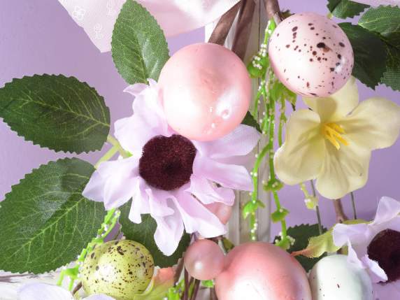 Rama de huevos de colores y flores artificiales.