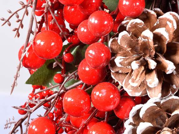 Zweig mit roten Beeren und schneebedeckten Tannenzapfen zum