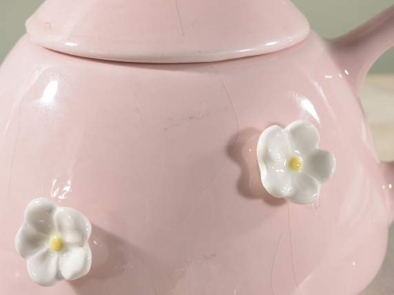Tetera y taza de cerámica con adornos de flores y conejos.
