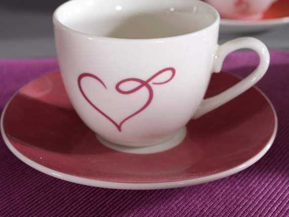 Taza de café de cerámica con corazón y platillo de colores.