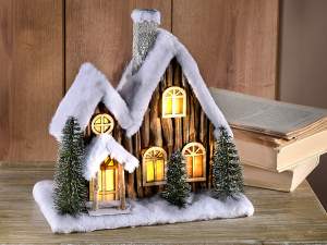 Mayorista casa de madera con capa de nieve y luces