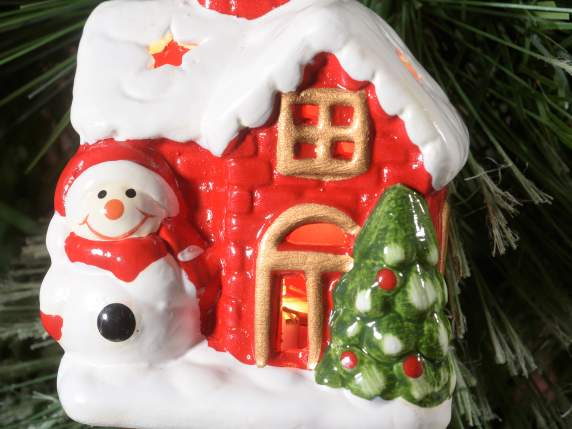 Casa de cerámica con personajes navideños y luces colgantes.