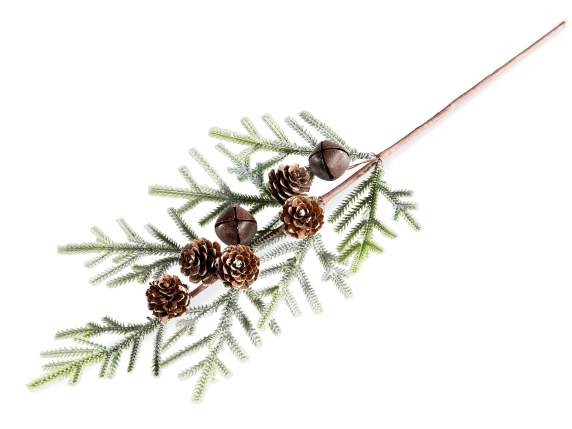 Artificial snow-covered fir branch with pine cones and bells