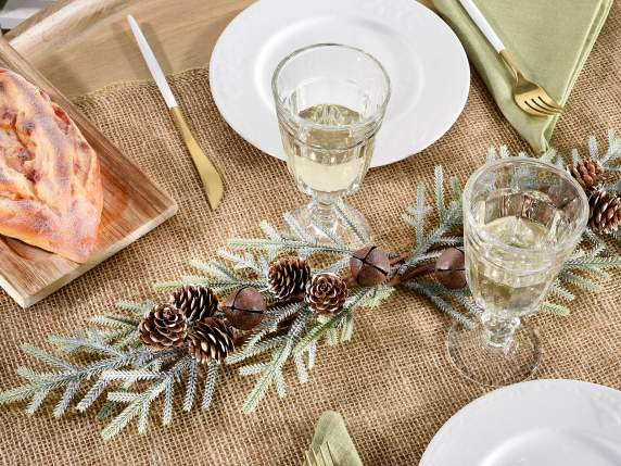Artificial snow-covered fir branch with pine cones and bells
